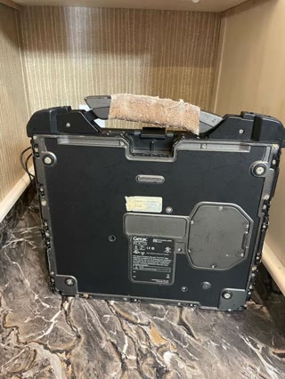 The underside — asset labels, sealed panels, and a carrying handle worn enough to need a wrap. Photograph by Rocky L. Oliver.
