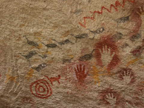 Hand stencils at Cueva de las Manos, Patagonia — sprayed pigment over living hands, mostly from around 7,300 BCE. Thousands of years later, the hands still wave (Suzko, CC BY-SA 3.0).