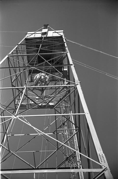 The Gadget being hoisted to the top of the Trinity tower, July 1945 — the first nuclear device, assembled by the physicists who would spend the rest of their lives reckoning with it (Manhattan Project photograph, public domain).