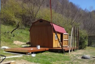 The shed — a 12×16 on a deck in the holler, red metal roof, wood siding. Home for three people, and the room where AdaLog was written. Photograph by Rocky L. Oliver.