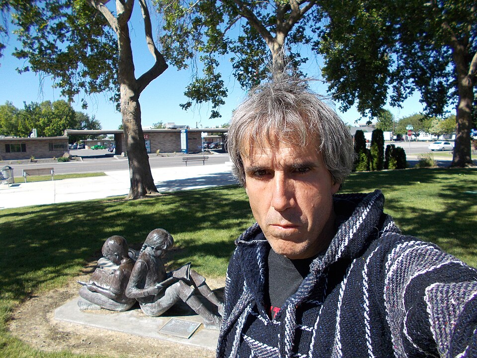 Terry A. Davis in 2017, taking a selfie in front of the public library in Richland, Washington, beside a statue of two children reading
